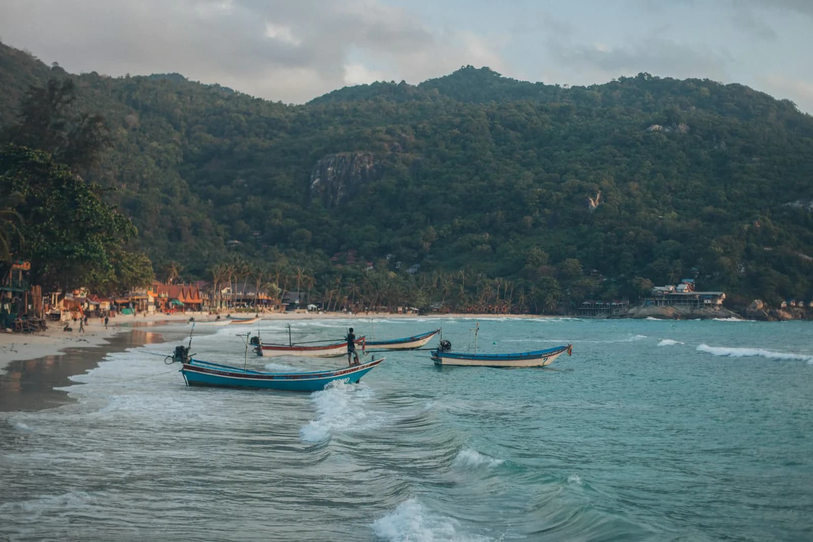Boats at Mai Khao Beach against green hills